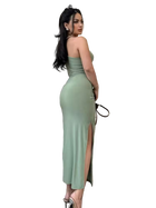 Woman wearing a green strapless dress with a slit on a white background