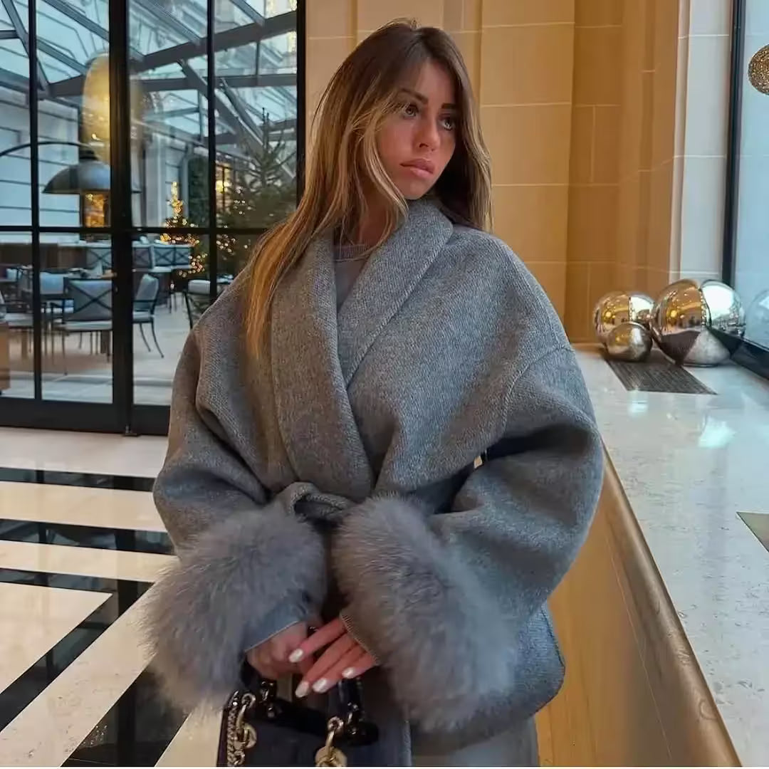 Woman wearing a gray coat with fur trim in an indoor setting