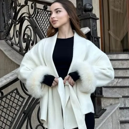 Woman wearing a white coat with fur trim standing on steps.