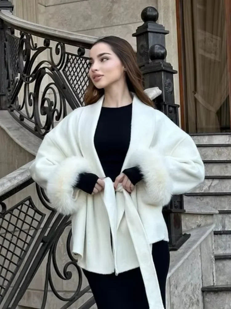 Woman wearing a white coat with fur trim standing on steps.