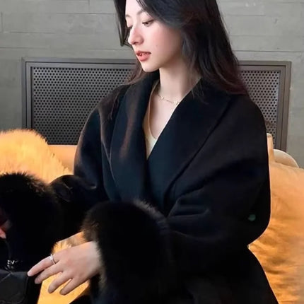 Woman in a black coat sitting on a couch with a dog.