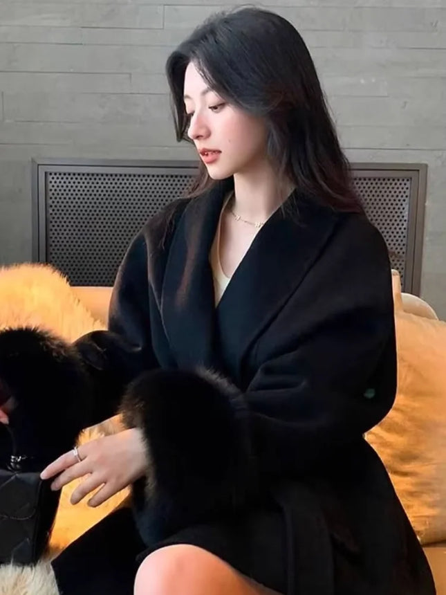 Woman in a black coat sitting on a couch with a dog.