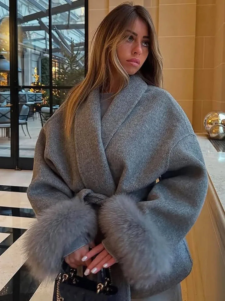 Woman wearing a gray coat with fur trim indoors