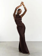 Woman in a brown evening gown posing against a white background