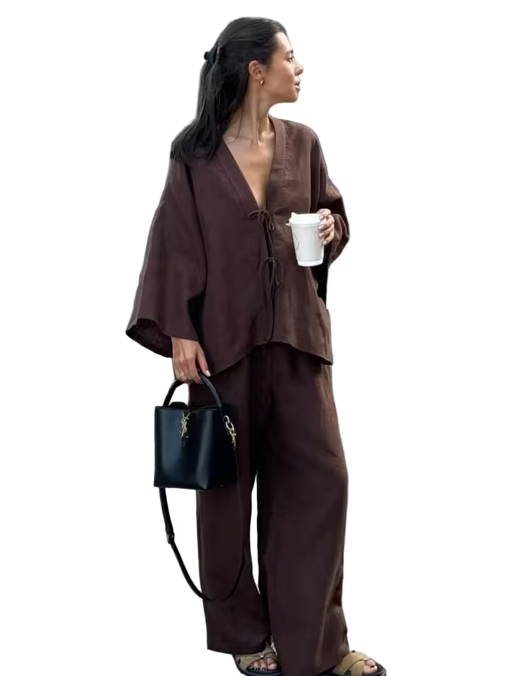 Woman in a brown outfit holding a black handbag and white cup on a transparent background