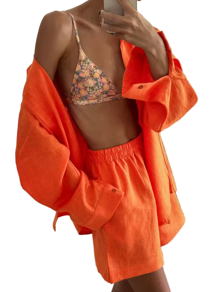 Person wearing a floral bikini top and orange shorts with jacket on a transparent background