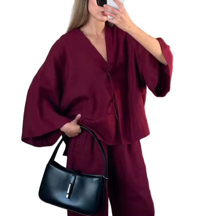 Woman in a burgundy outfit holding a black handbag, taking a mirror selfie.