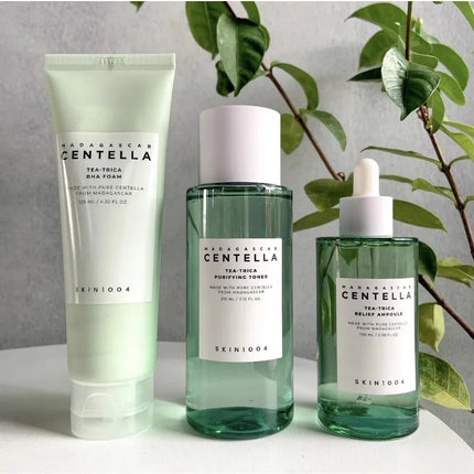 Three skincare products from SKIN1004 with green and white labels on a neutral background.