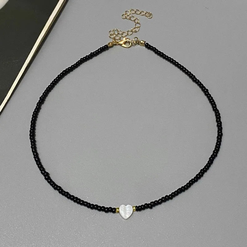 Black beaded necklace with a heart-shaped pendant on a gray surface