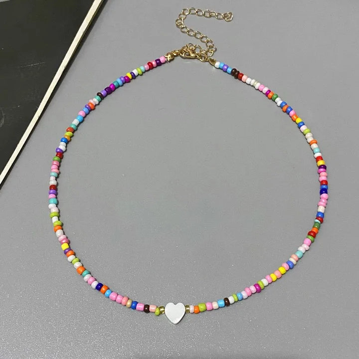 Colorful beaded necklace with a heart charm on a gray surface