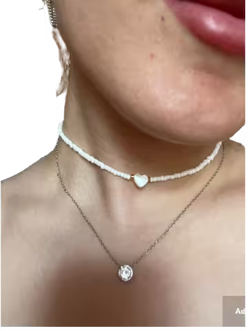 Close-up of a necklace with a heart-shaped pendant worn by a person.