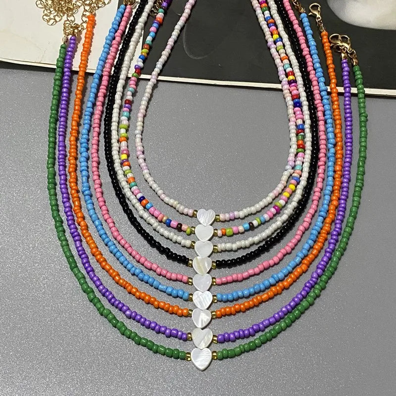 Colorful beaded necklaces with heart-shaped beads on a gray surface