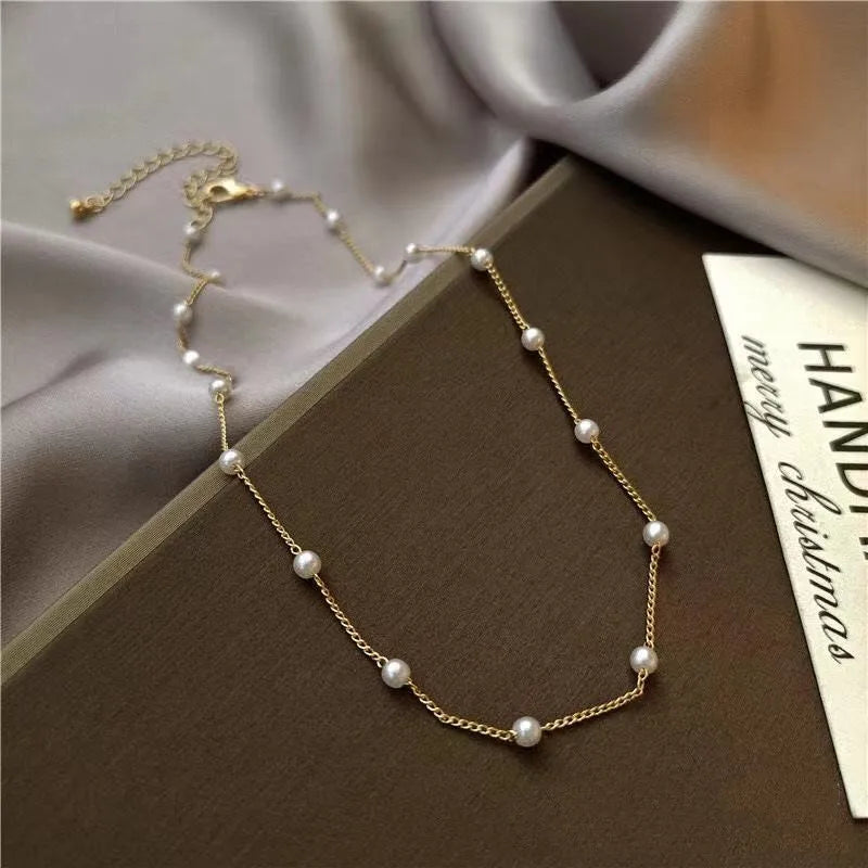Gold necklace with pearl beads on a brown surface