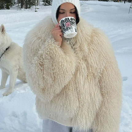 Person in a fluffy white coat holding a mug in a snowy landscape with a dog.
