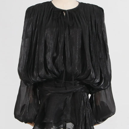 Black sheer blouse on a mannequin against a white background
