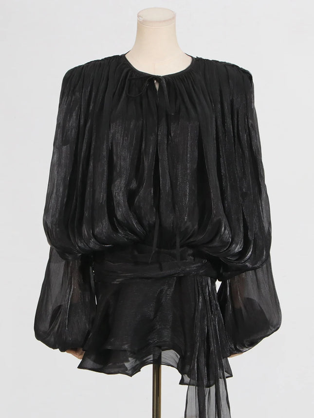 Black sheer blouse on a mannequin against a white background