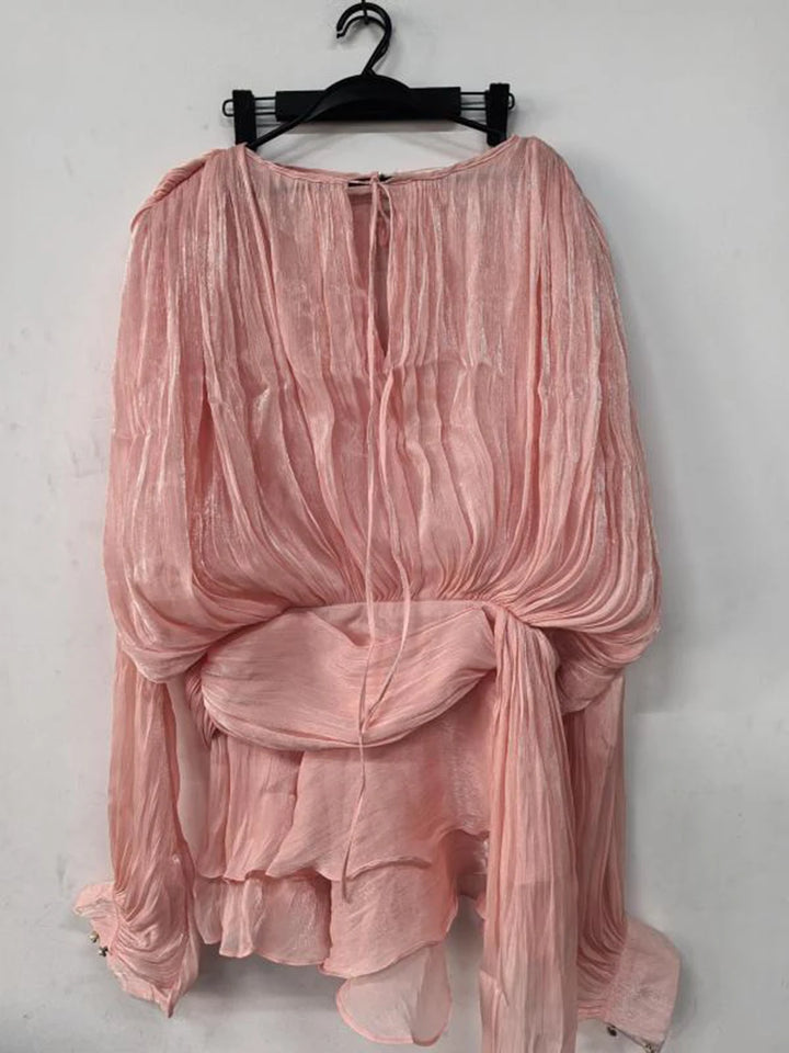 Pink sheer top on a hanger against a white background