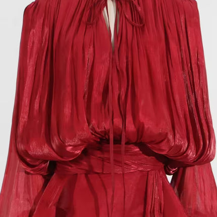 Red sheer blouse on a mannequin against a white background