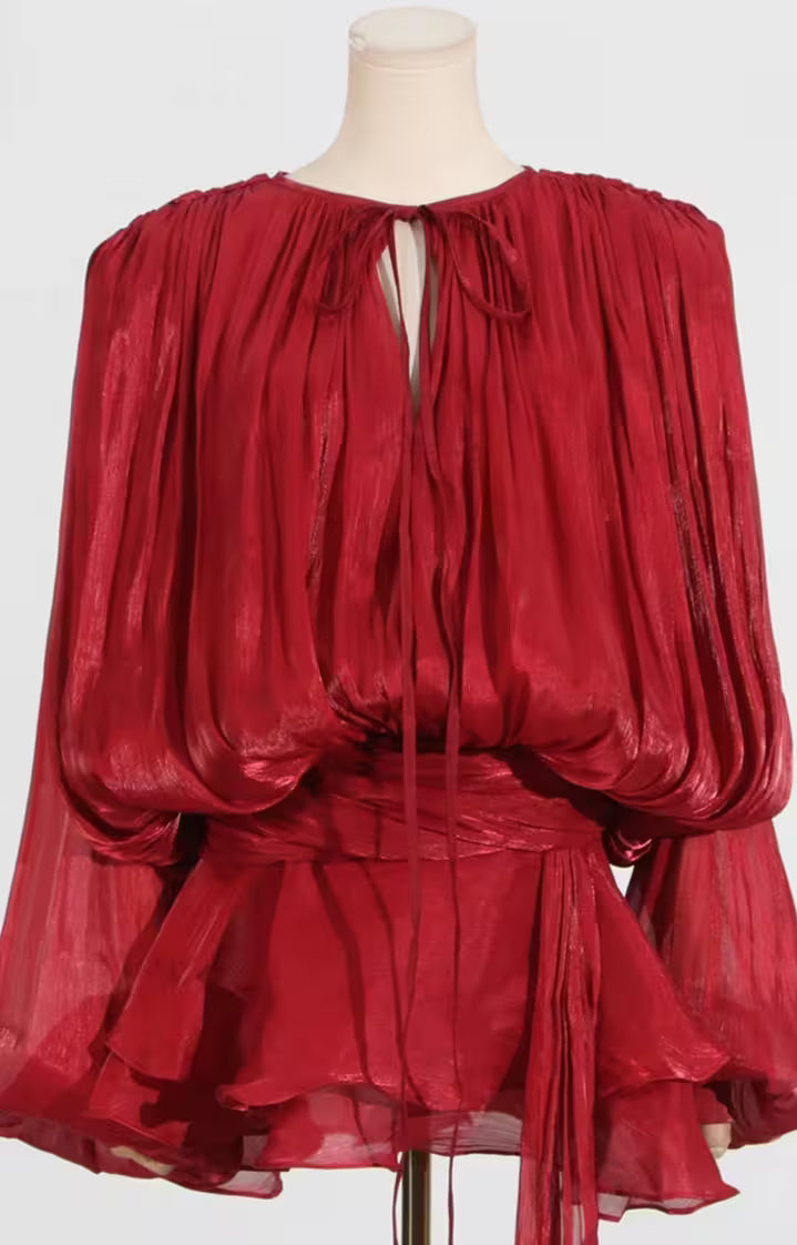 Red sheer blouse on a mannequin against a white background