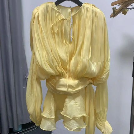 Yellow outfit on a hanger against a white wall