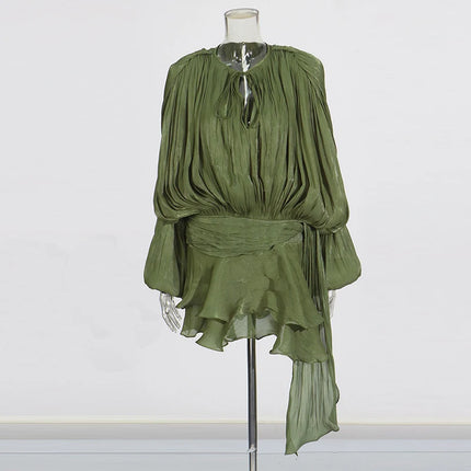 Green pleated dress on a mannequin against a white background