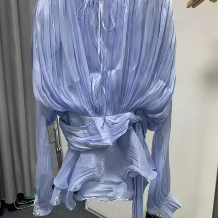 Light blue sheer blouse on a hanger against a neutral background
