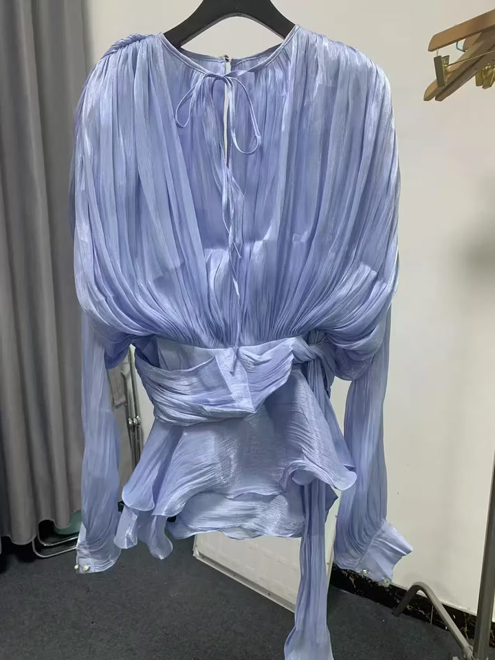 Light blue sheer blouse on a hanger against a neutral background