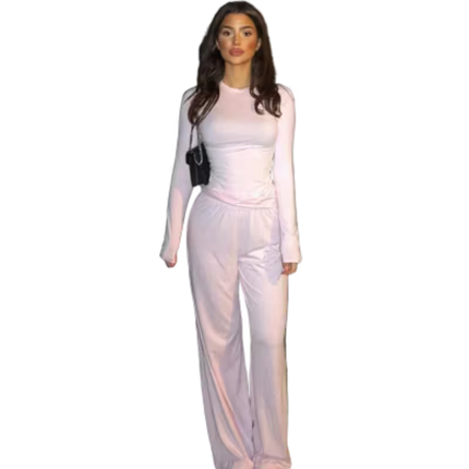 Woman wearing a light pink outfit with a black handbag on a white background
