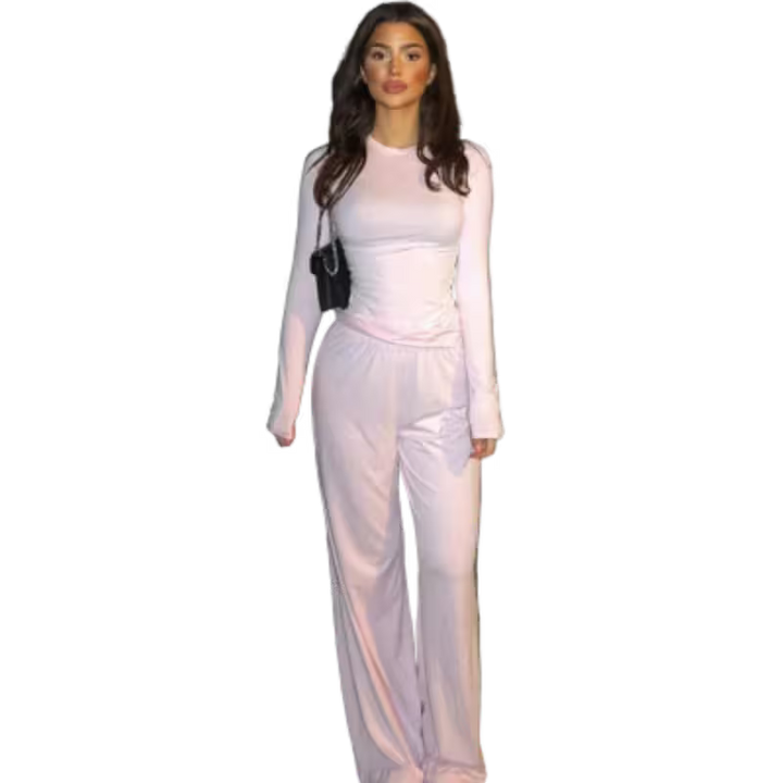 Woman wearing a light pink outfit with a black handbag on a white background