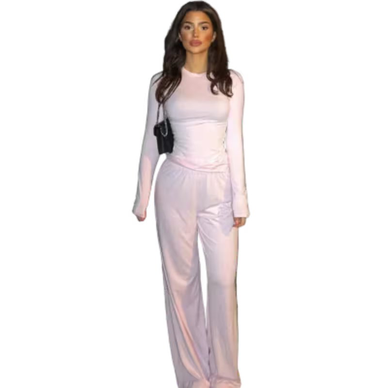 Woman wearing a light pink outfit with a black handbag on a white background