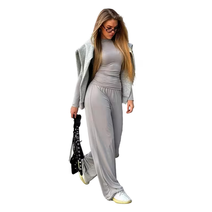 Woman in gray outfit with long hair and glasses on a white background