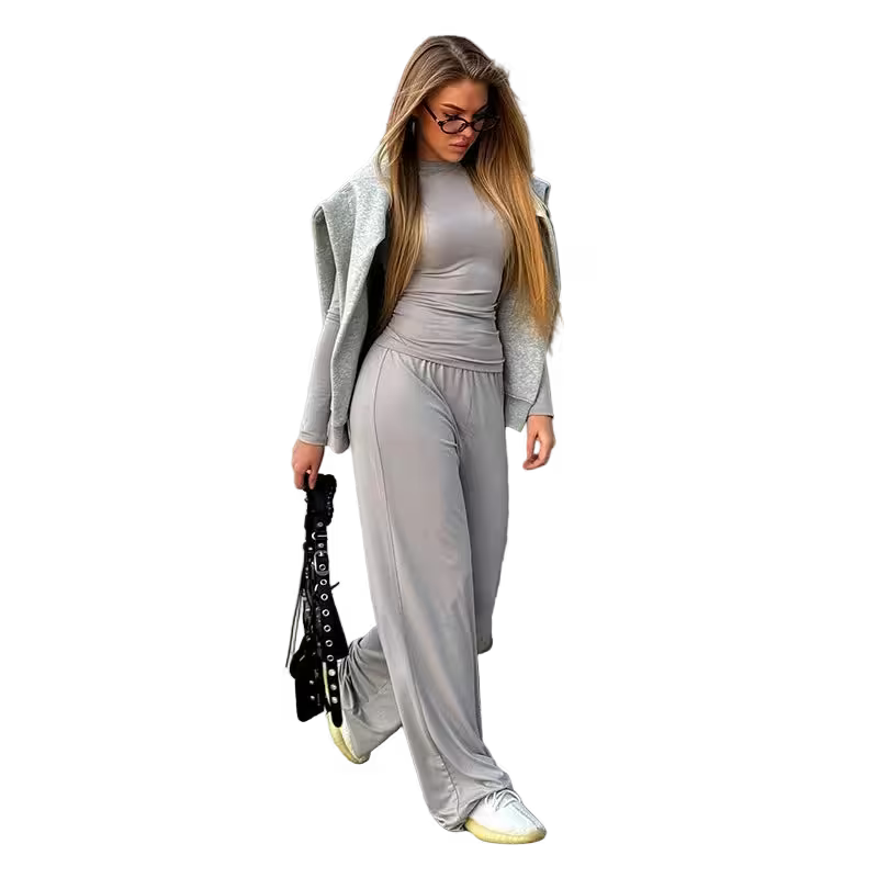 Woman in gray outfit with long hair and glasses on a white background