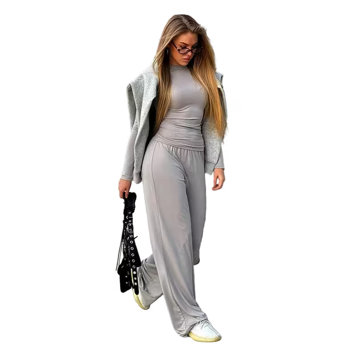Woman in gray outfit with long hair and glasses on a white background