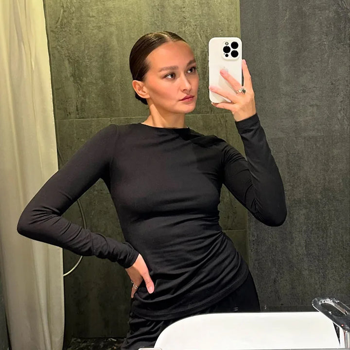 Person wearing a black long-sleeve top taking a mirror selfie.