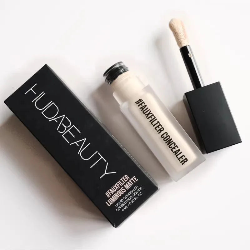 Huda Beauty concealer with applicator and packaging on a white background