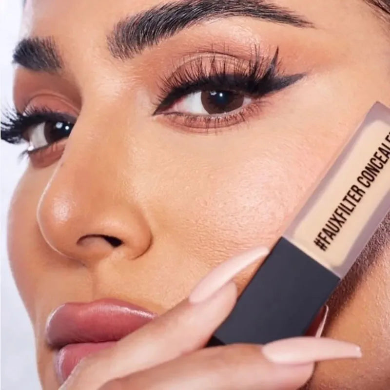 Close-up of a woman applying concealer stick to her face.
