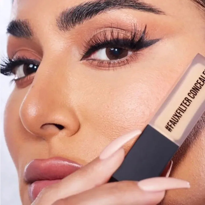 Close-up of a woman applying concealer stick to her face.