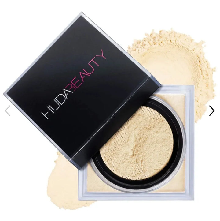 HUDA BEAUTY powder compact with open lid showing light beige powder on a white background