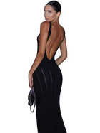Woman wearing a black evening gown with a low back design, holding a clutch.