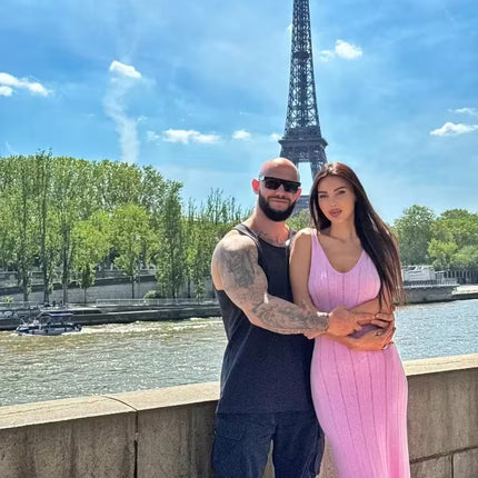 Two people posing in front of the Eiffel Tower with a clear blue sky.