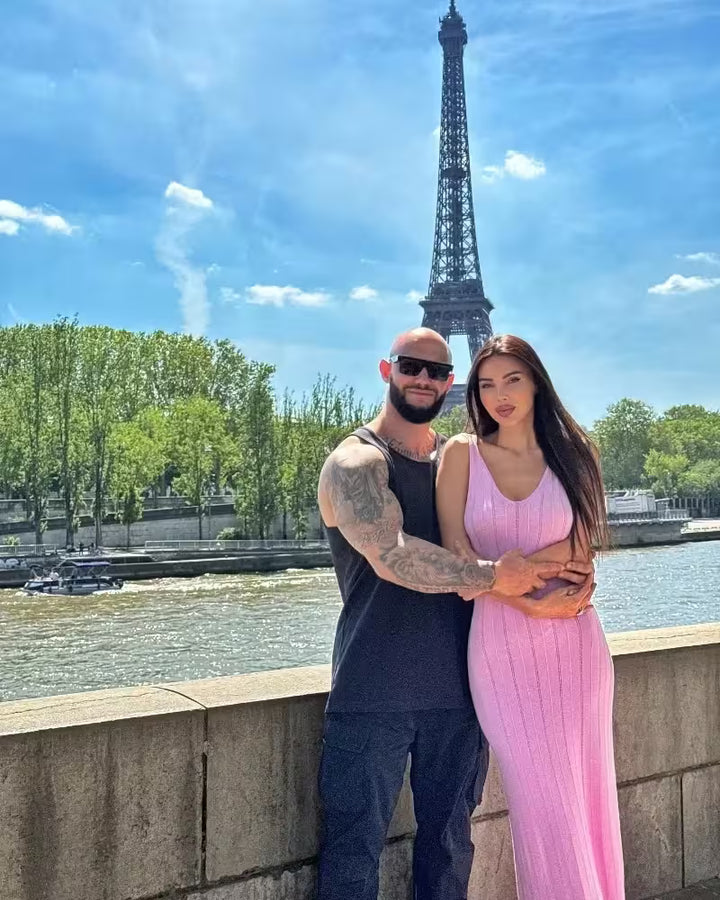 Two people posing in front of the Eiffel Tower with a clear blue sky.