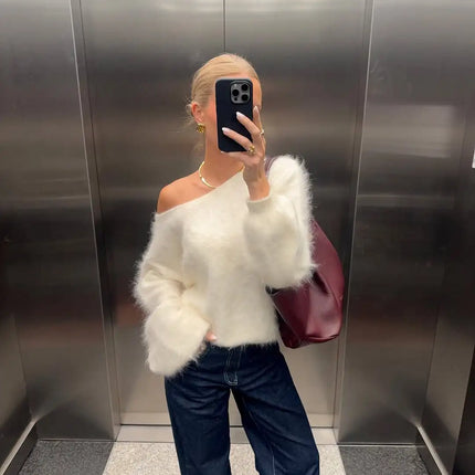 Person wearing a white fluffy sweater and dark jeans in an elevator.