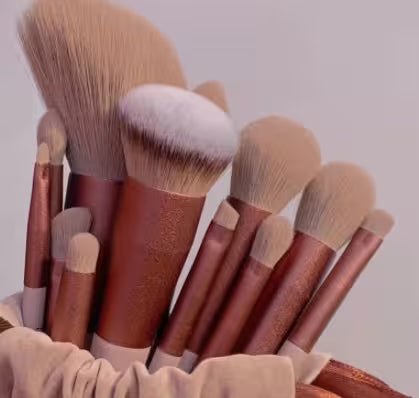 Set of makeup brushes with brown handles and white bristles in a basket.