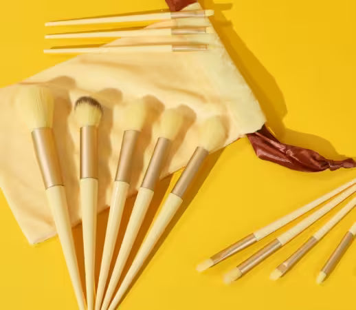 Set of makeup brushes with a beige pouch on a yellow background
