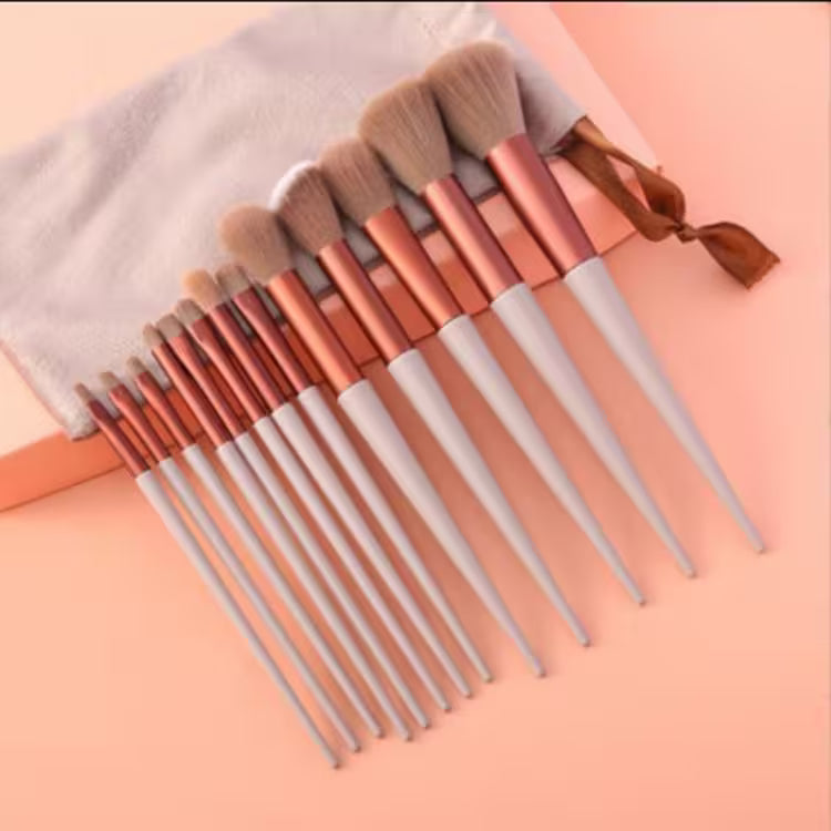 Set of makeup brushes with rose gold and silver handles on a pink background