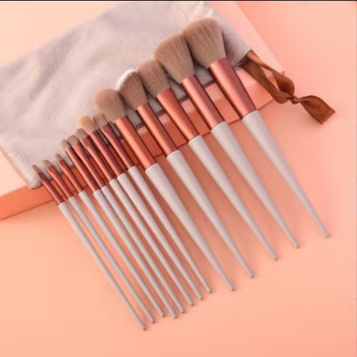 Set of makeup brushes with rose gold and silver handles on a pink background