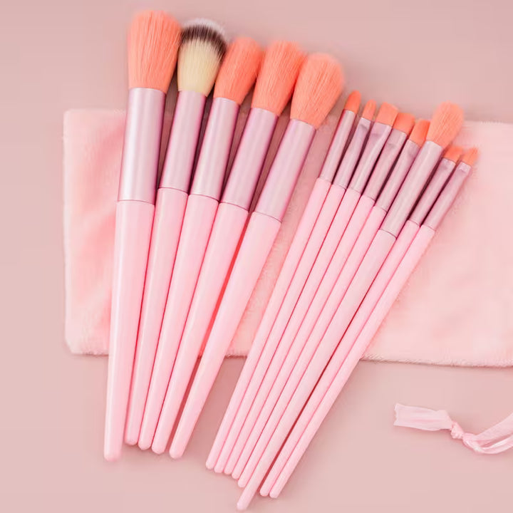 Set of pink makeup brushes with a pink pouch on a matching background