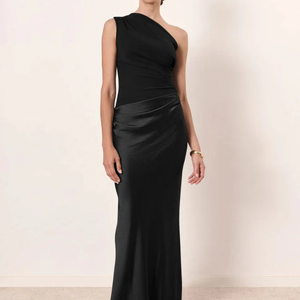 Woman wearing a black one-shoulder gown against a plain background