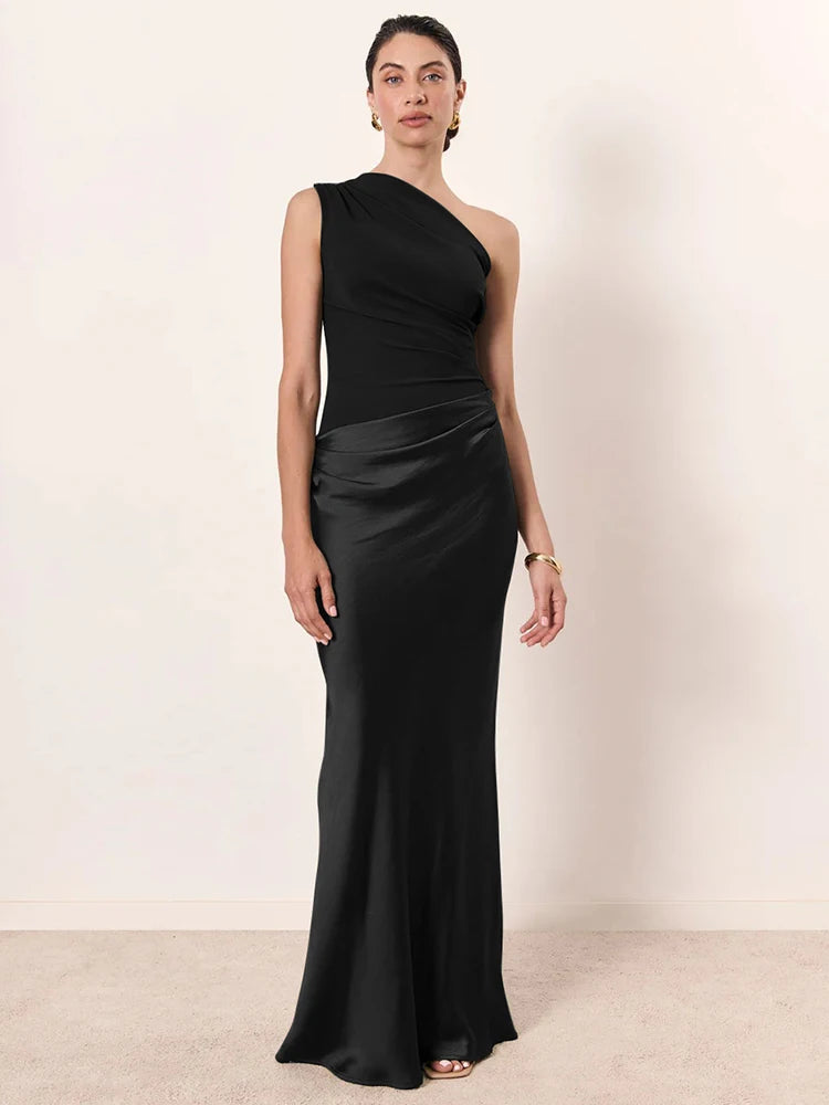 Woman wearing a black one-shoulder gown against a plain background