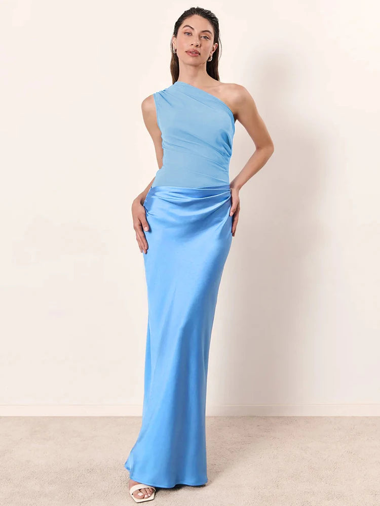 Woman wearing a light blue one-shoulder gown against a plain background
